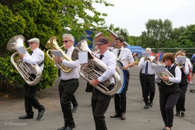 Band playing brass instruments during an outdoor event.