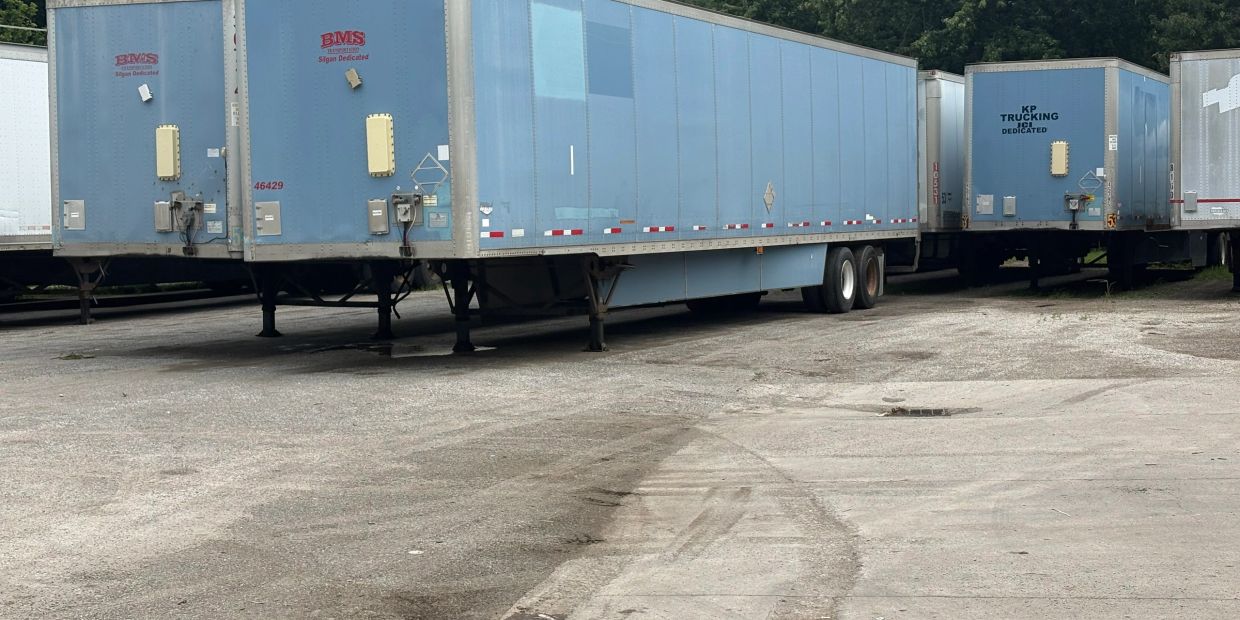Several blue semi-truck trailers parked in a lot.