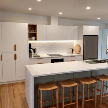 Modern kitchen with white cabinets and wooden stools.