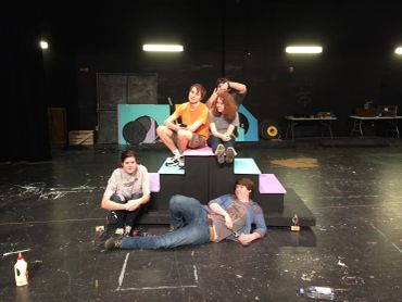 Four people posing on a stage with block props.