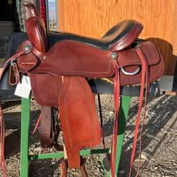 A brown leather Western saddle resting on a green metal saddle stand.