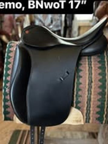 Black leather horse saddle displayed on a patterned cloth.