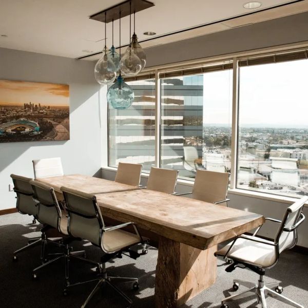 Modern conference room with large wooden table and city view.