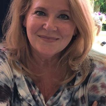 Smiling woman with blonde hair in a tie-dye top.