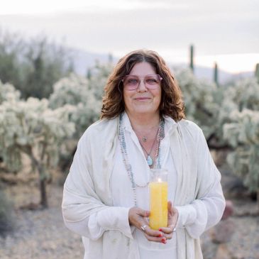 A woman in light clothing holding a yellow candle outdoors.