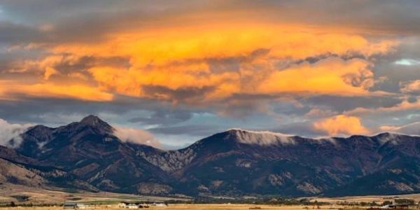 Orange cloud over mountain range at sunset.