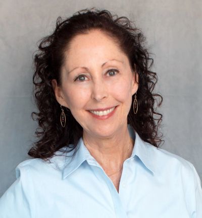 Smiling woman with curly hair in a light blue shirt.