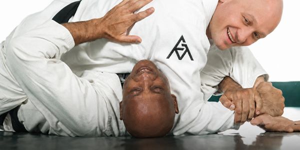 Two men practicing Brazilian Jiu-Jitsu grappling on the mat.