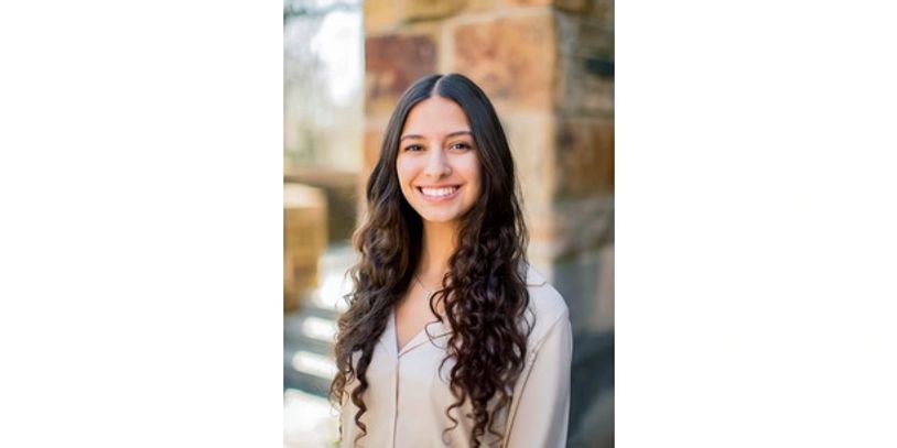 Smiling young woman with long curly hair outdoors.