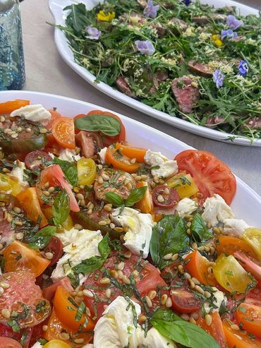 a plate of isle of wight tomatoes with mozarella, basil and toasted pinenuts.