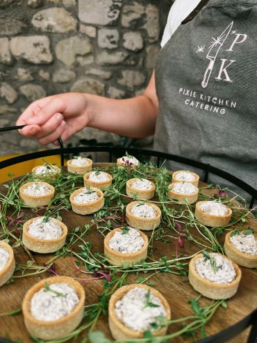 Person holding tray of savory tartlets with herbs.