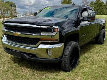 Black Chevrolet pickup truck parked on grass under a partly cloudy sky.