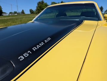 Close-up of a 351 Ram Air engine hood on a yellow car.