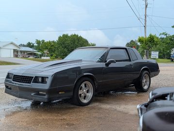 A sleek black classic coupe car parked on a wet driveway.
