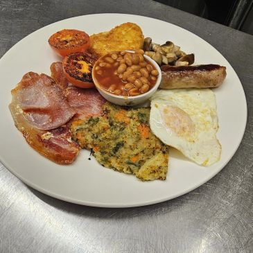 A full English breakfast with eggs, sausage, bacon, beans, mushrooms, tomatoes, hash brown, and vegetable patty.