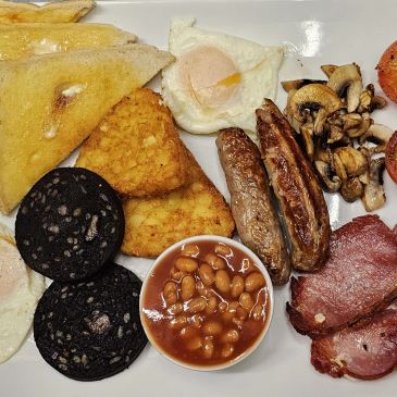 Full English breakfast with eggs, sausages, beans, toast, mushrooms, and black pudding.
