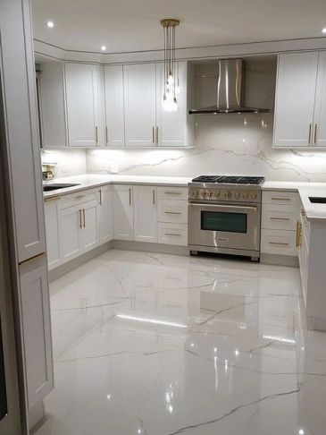 Modern white kitchen with marble floors and gold accents.