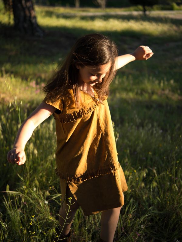 Niña bailando en el campo al atardecer.