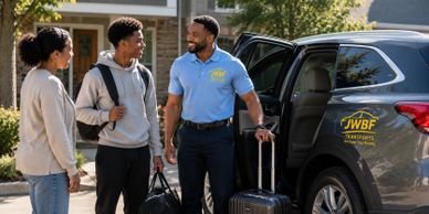 Friendly driver greeting two young passengers near a vehicle with JWBF Transports logo.