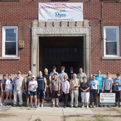 Group of people standing in front of Dom Polski building for a community center project.