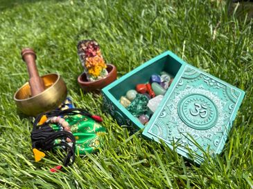 Spiritual items including crystals, a singing bowl, and sage on grass.