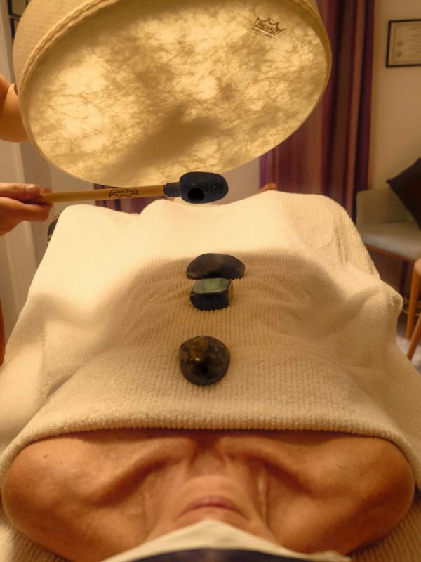 Person receiving sound therapy with stones on their back.