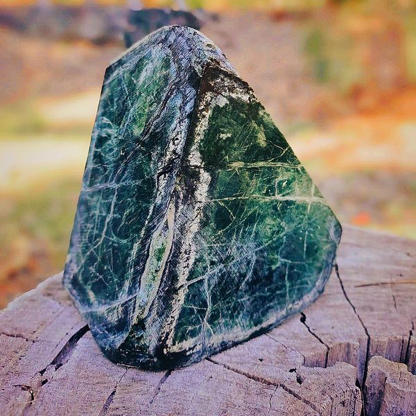 A polished green stone on a wooden surface.