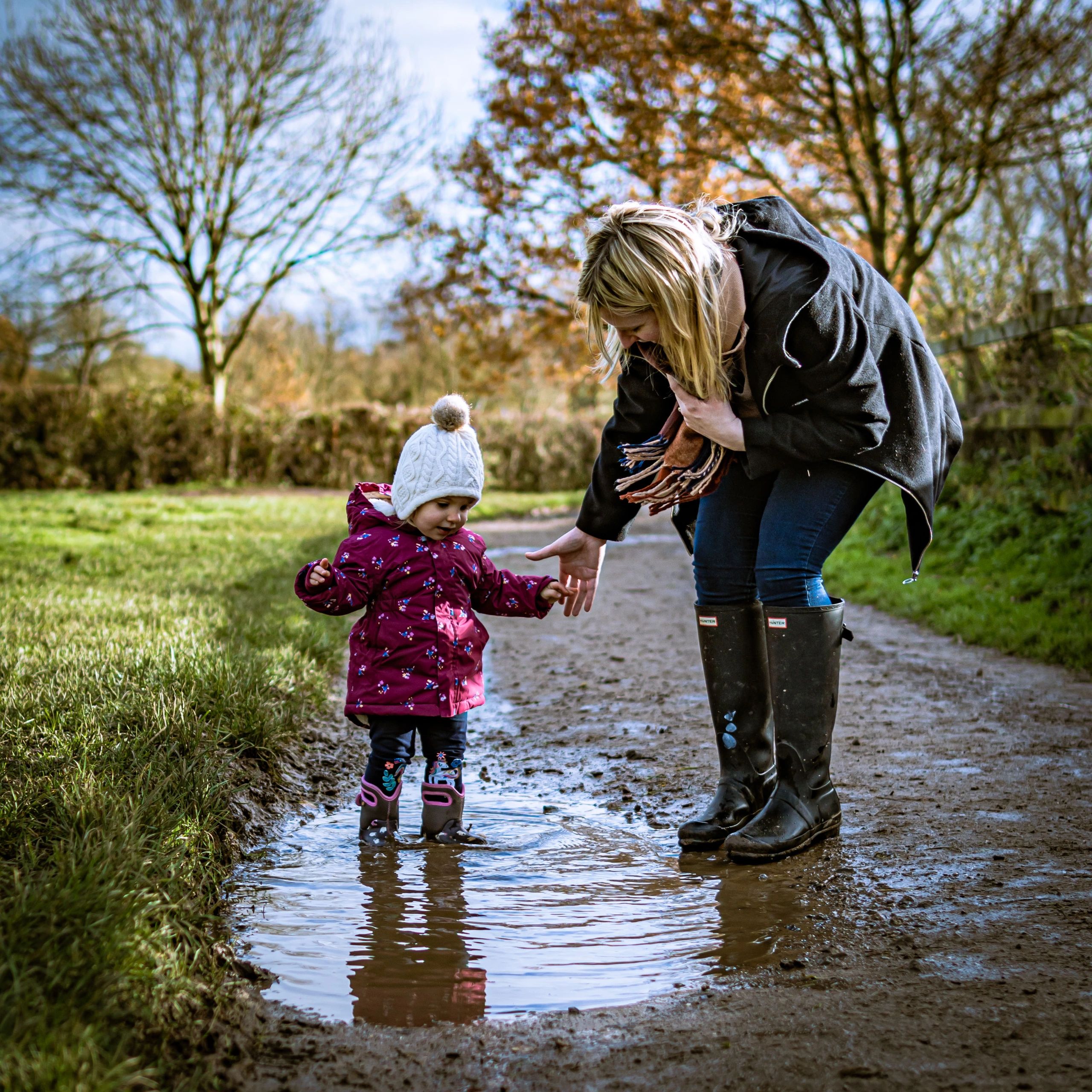 Happy little girl with her family jumping in puddles during a photoshoot