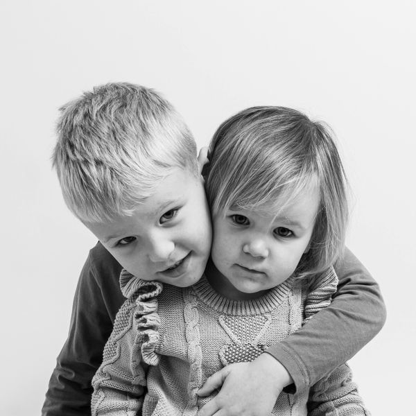 A brother and sister pose hugging smiling for a photograph