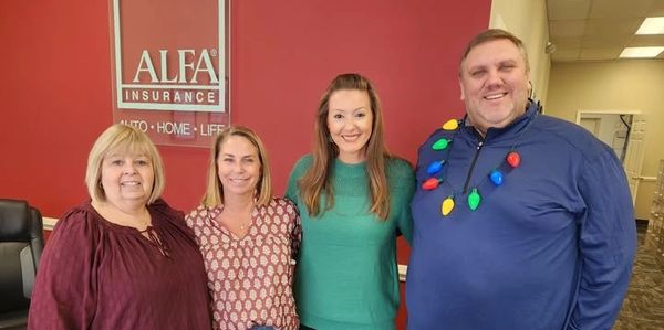 Four people smiling indoors at an Alfa Insurance office.
