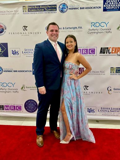 Couple dressed formally posing on red carpet.