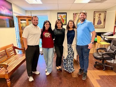 Group of five people posing indoors with smiles.