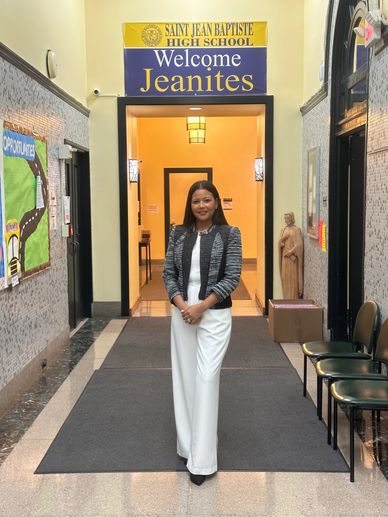 Woman standing under a school welcome sign.