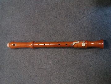 A wooden recorder musical instrument lying on a carpet.