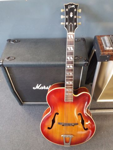 Vintage Gibson hollow body guitar leaning against a Marshall amplifier.