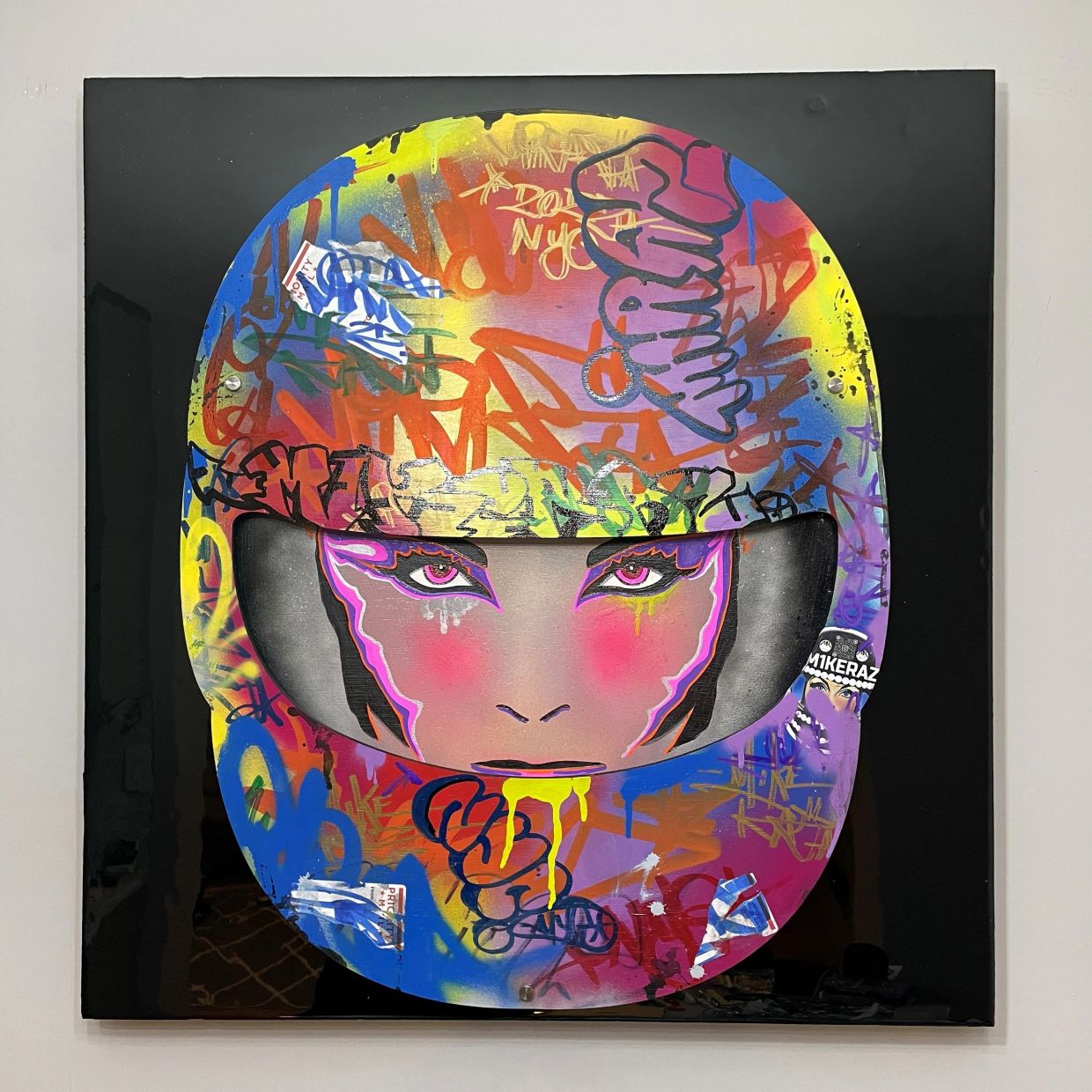 Graffiti art of a face wearing a colorful helmet.