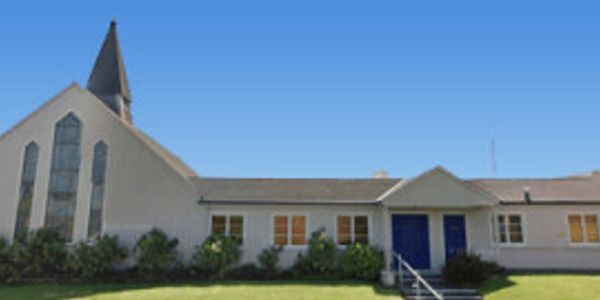 A white church building with a tall steeple under a clear blue sky.