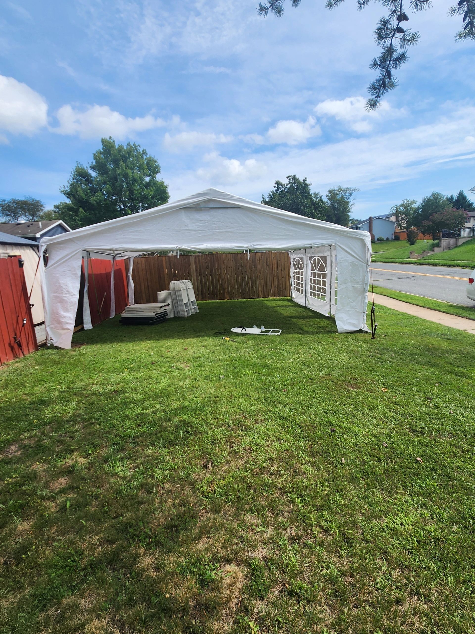 White outdoor tent setup in a backyard on a sunny day.