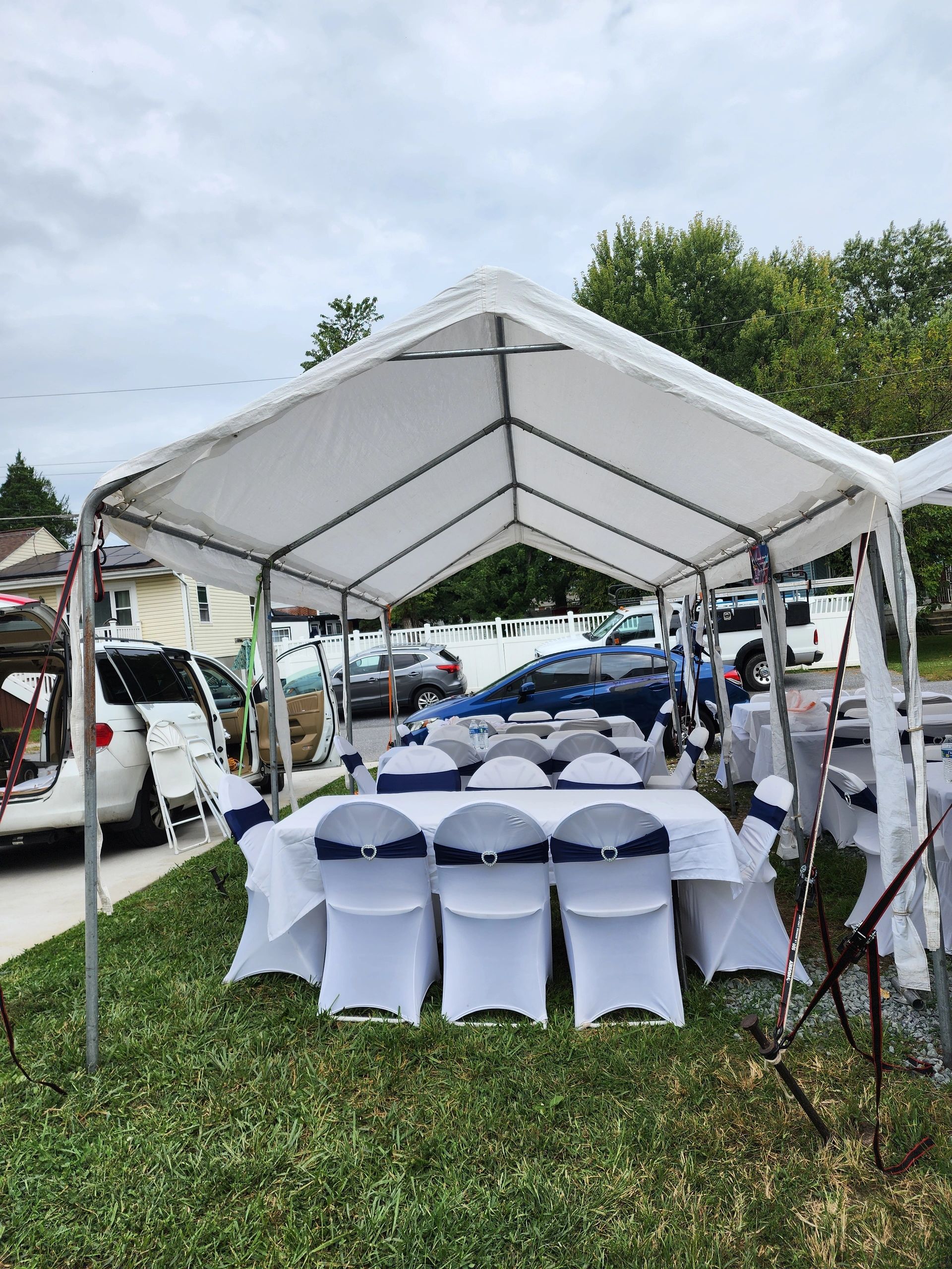 Outdoor event setup with white tent and decorated chairs.
