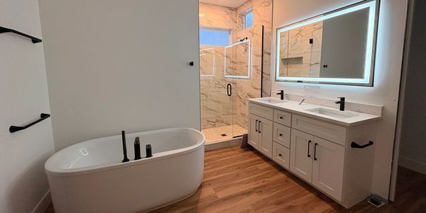 Modern bathroom with a freestanding tub and illuminated mirror.