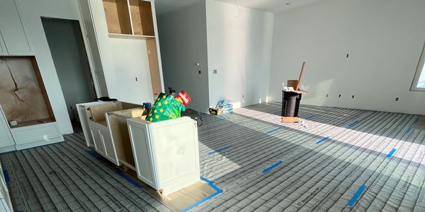 Unfinished room with construction materials and floor heating installation.