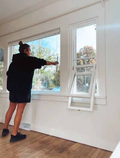 Person cleaning a large window indoors.