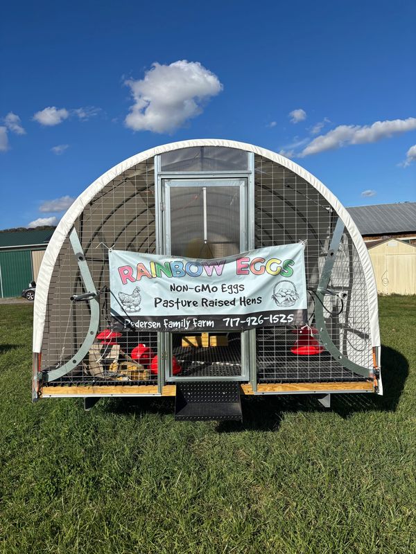 Mobile chicken coop with sign advertising Rainbow Eggs from pasture raised hens.