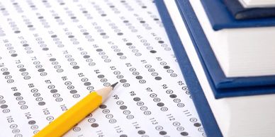 A pencil on a multiple-choice answer sheet with stacked books nearby.