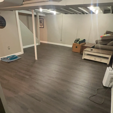 Spacious basement with gray flooring and minimal furniture.