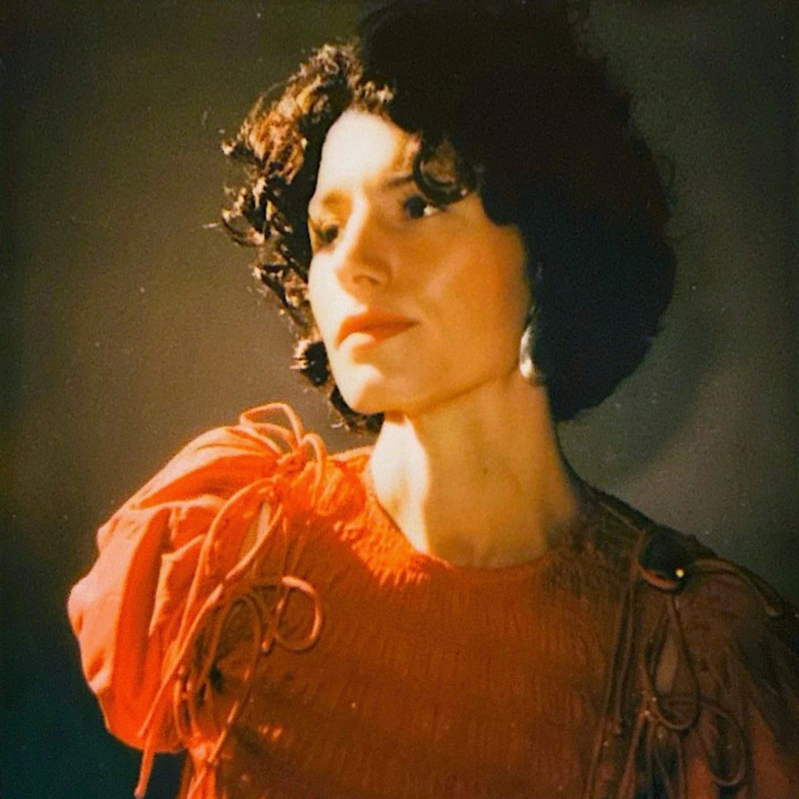 Woman with curly hair in an orange dress.