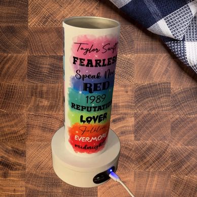Colorful Taylor Swift album-themed lamp on a wooden surface.