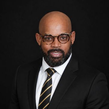 Confident man in glasses and suit against black background.