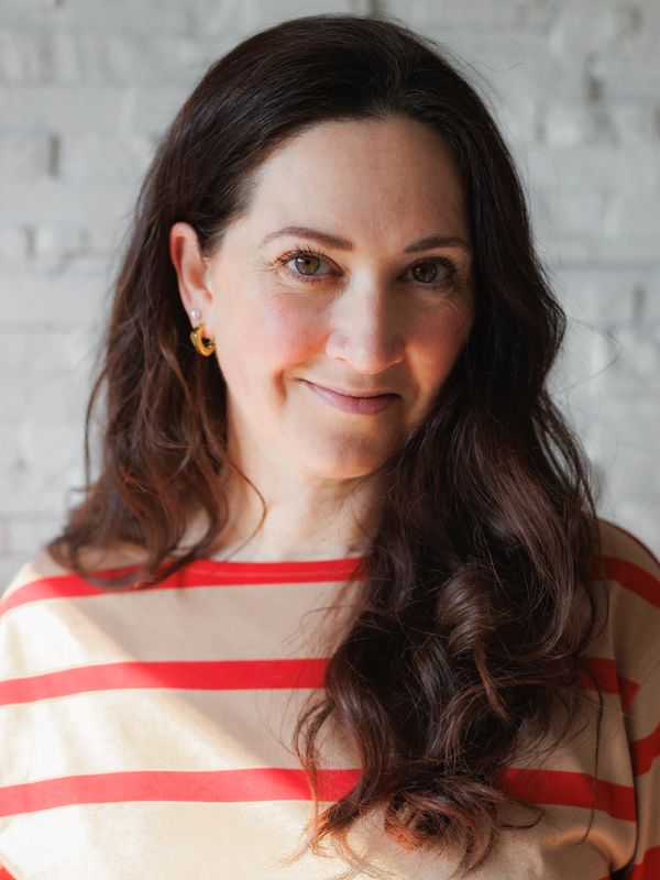 Woman with long dark hair wearing a striped shirt smiles gently.