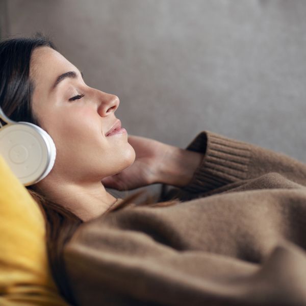 Woman relaxing with eyes closed, listening to music on headphones.